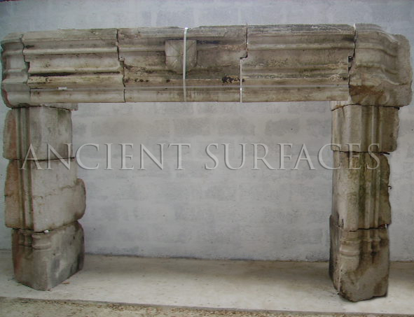 Unrestored reclaimed French limestone fireplace mantel from Ancient Surfaces with a moulded three part lintel and block jambs, still banded and standing against a block wall in the salvage yard